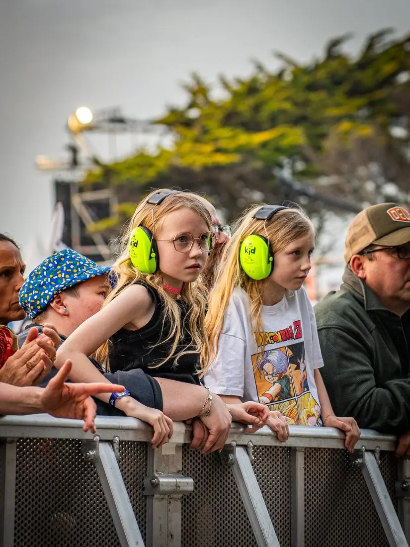 Enfants au premier rang d’un concert en plein air, casques antibruit sur les oreilles